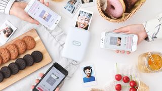 One of the best portable printers, the Instax Mini Link, on a table covered with food and instant photographs